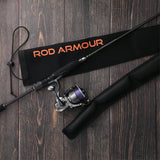 Spinning rod beside Rod Armour Pro sleeve on dark wood floor lifestyle shot
